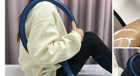 A client seated on a treatment couch with a large loop applicator held across the leg during a combined radiofrequency and magnetic-field session in a clinic room